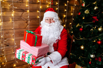 Fototapeta na wymiar Merry Christmas. Santa Claus near Christmas tree with gifts