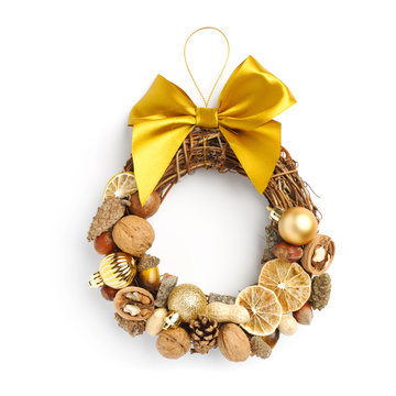 Beautiful Christmas wreath consisting of dried orange slices, nuts, cones, decorated with a large yellow bow on a white background