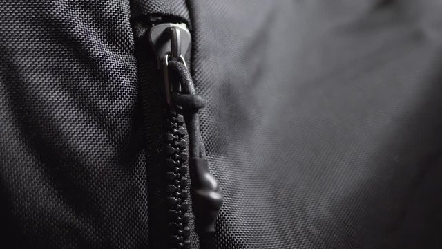 Man unzips and zips black sport backpack.