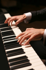 Hands on piano. The pianist plays the piano. Piano keys on black background