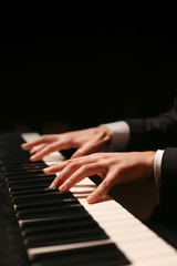 Fototapeta na wymiar Hands on piano. The pianist plays the piano. Piano keys on black background