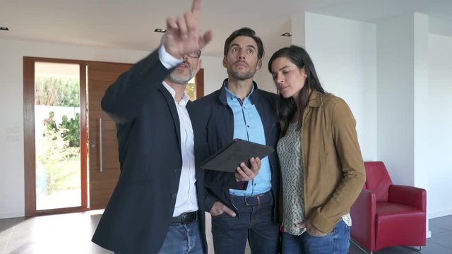 Real estate agent showing modern house to potential buyer couple