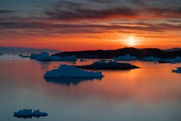 Sunset time on the arctic ocean with icebergs