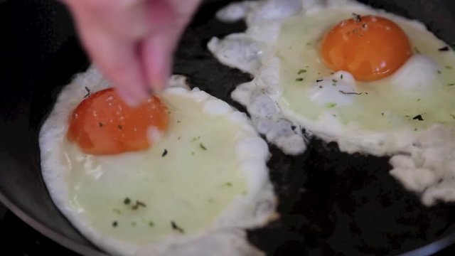 Eier werden in die Pfanne gegeben, gew&uuml;rzt und zu Spiegeleiern gebraten, full HD 1080p Video 25 fps
