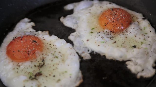 Eier werden in die Pfanne gegeben, gew&uuml;rzt und zu Spiegeleiern gebraten, full HD 1080p Video 25 fps