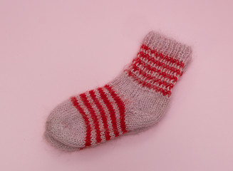 Obraz na płótnie Canvas handmade woolen merino wool socks on pink rose background. craft store concept