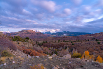 Obraz premium A distant snow capped mountain range in front of rolling green farm land