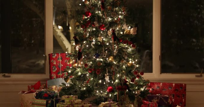 Illuminated Christmas tree and presents at night