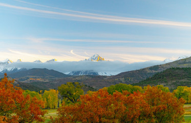 The sun is about to set over a ranch in the colorado mountains filled with cows and surrounded by fences