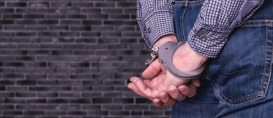 Cropped image of male hands in handcuffs behind his back