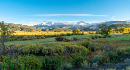 Obraz premium The sun is about to set over a ranch in the colorado mountains filled with cows and surrounded by fences