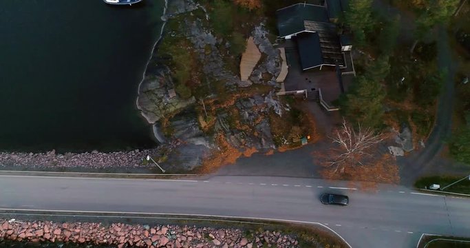 Car in the archipelago, C4K aerial, tracking, drone shot, following a car driving on a asphalt road, between islands and over bridges, in the finnish saaristo, on a cloudy day, Finland