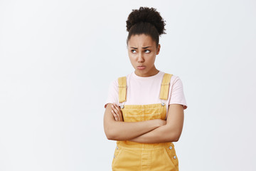 Offended upset and jealous young female student with dark skin, frowning and sulking, pursing lips,...