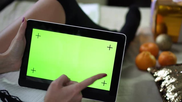A woman uses a tablet with a blank green screen.