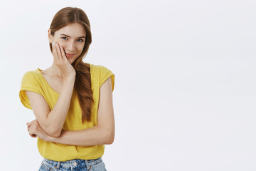 Waist-up shot of cute feminine girlfriend in yellow-thisrt touching cheek gently smiling sensually...