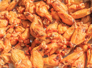 Fried Naked Chicken Wings: Fried naked chicken wings in a foil tray just after being cooked.