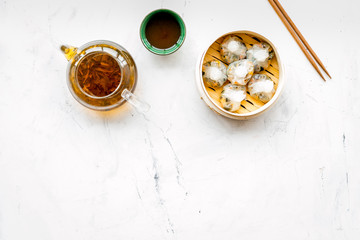 Dim sums with sticks and herbal tea in Chinese restaurant on marble background top view mockup