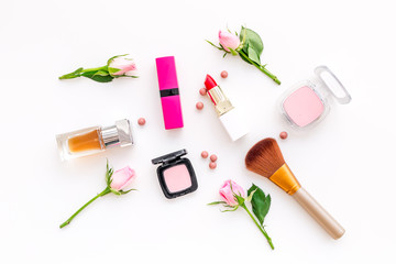 Makeup products for young girls. Composition with cosmetics with rose tones. Lipstick, bulk, eyeshadow, perfume, brushes and rose flowers on white background top view