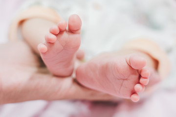 Obraz na płótnie Canvas Baby feet in mother hands. Tiny Newborn Baby's feet on female Shaped hands closeup. Mom and her Child. Happy Family concept.