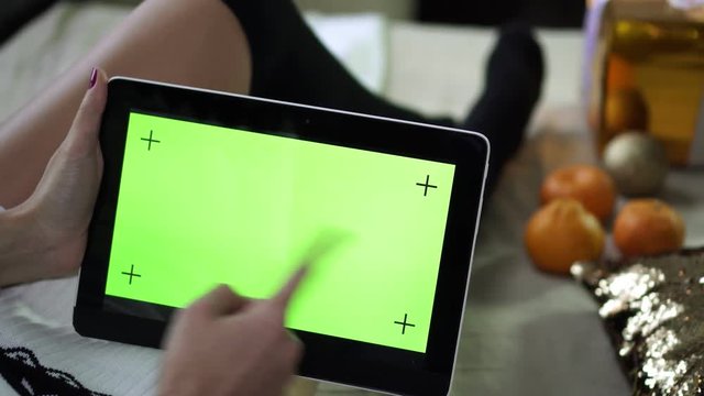 A tablet computer with a clean green screen in the hands of a woman.