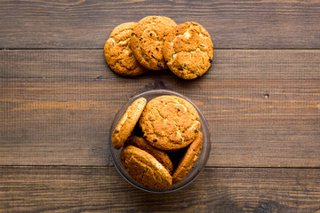 Homemade oatmeal cookies in glass bowl on dark wooden background top view copy space
