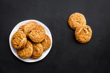 Homemade oatmeal cookies on white plate on black background top view copy space