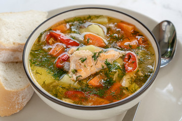 Salmon soup with potatoes, carrots, dill, pepper in bowl, close up