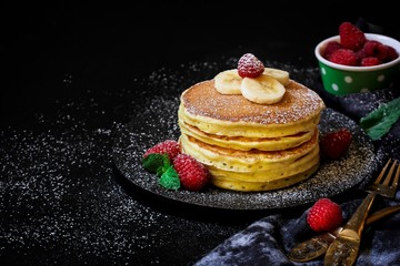 Stack of homemade fluffy pancakes on dark moody background