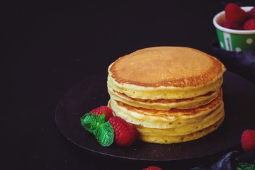 Stack of homemade fluffy pancakes on dark moody background
