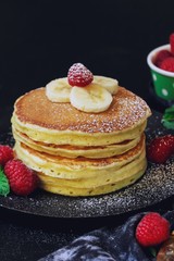 Stack of homemade fluffy pancakes on dark moody background