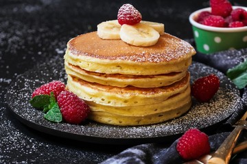 Stack of homemade fluffy pancakes on dark moody background
