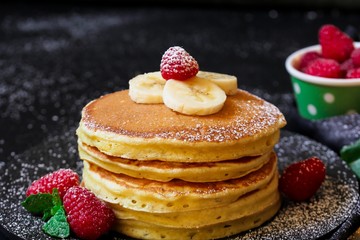Stack of homemade fluffy pancakes on dark moody background