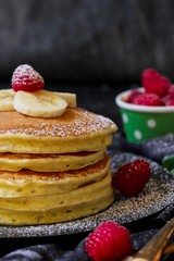Stack of homemade fluffy pancakes on dark moody background