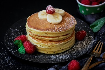Stack of homemade fluffy pancakes on dark moody background