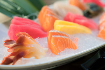 Mixed sliced fish sashimi on ice in white bowl. Sashimi Salmon Tuna Hamachi Prawn and Surf Calm set, raw fish, japanese food in Asian restuarant.