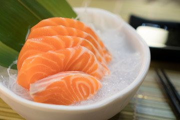 Raw salmon slice or salmon sashimi in Japanese style fresh serve on ice in bowl.