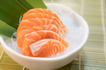 Raw salmon slice or salmon sashimi in Japanese style fresh serve on ice in bowl.