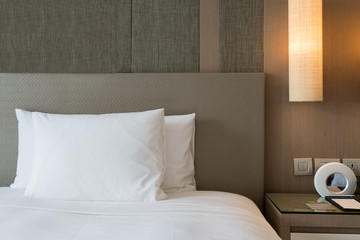Close up fragment of bedroom with reading lamp and digital alarm clock in modern home or hotel.