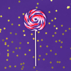 Big lollipop on solid ultra violet background with golden sprinkles