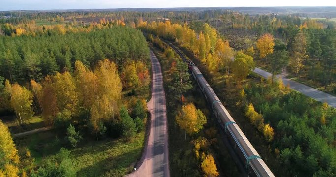 Train in a autumn color landscape, C4K aerial, tracking, drone shot, following a long cargo train, driving on the countryside, on a sunny, fall day, in Uusimaa, Finland