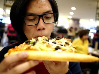 Fotobehang Pizzeria Asian teen eating a big pizza