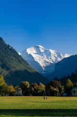 Peolpe in green field Hohematte park and Swiss alps in Interlaken, Switzerland