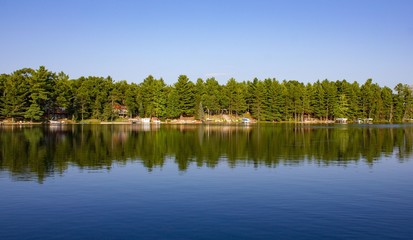 Lake reflection of evergreens and blue sky in early fall