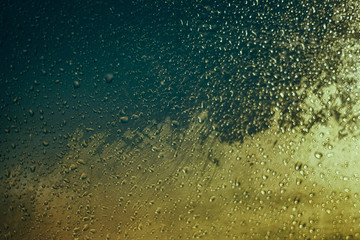 Water drops on car side glass in dusk and bokeh lights