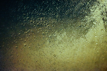 Water drops on car side glass in dusk and bokeh lights