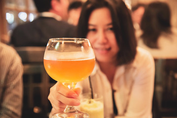 Happy lady shows a big glass of beer in restaurant - celebration beer cheers concept