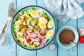 Bowl with wheat porridge, boiled quail eggs and fresh vegetable salad of radish, corn, sweet pepper and chinese cabbage. Healthy and delicious dietary lunch. Vegetarian, vegan food. Top view. Flat lay