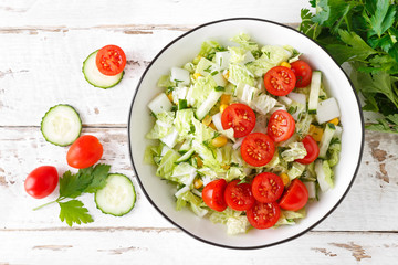 Healthy vegetable salad of chinese cabbage, corn, cucumbers and tomatoes. Delicious vegetarian dietary lunch. Vegan food. Top view. Flat lay