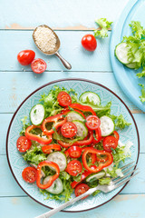 Healthy vegetarian vegetable salad of fresh lettuce, cucumber, sweet pepper and tomatoes. Vegan plant-based food. Flat Lay. Top view