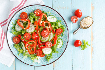 Healthy vegetarian vegetable salad of fresh lettuce, cucumber, sweet pepper and tomatoes. Vegan plant-based food. Flat Lay. Top view